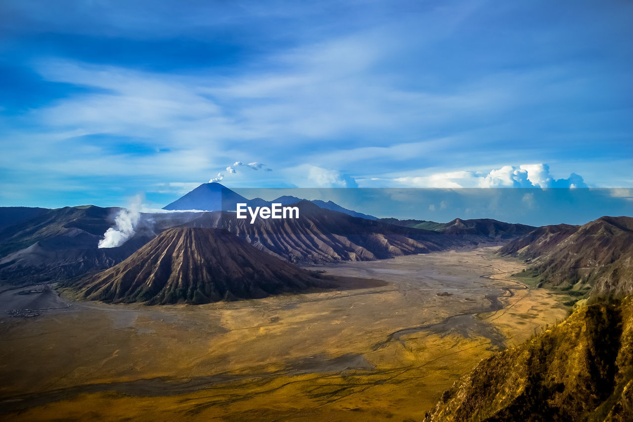 Volcanic crater and landscape against cloudy sky