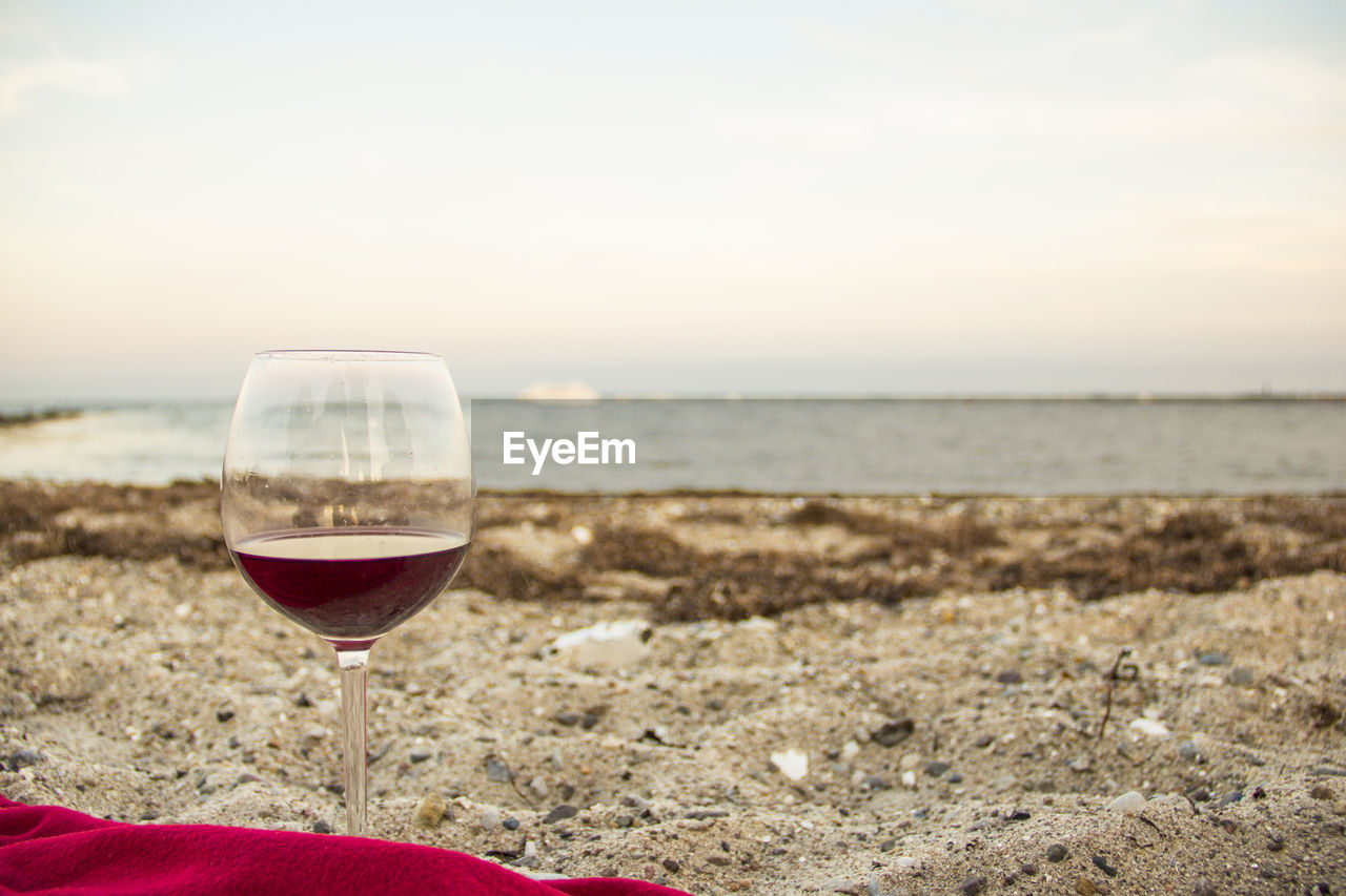 Red wine in wineglass at beach during sunset