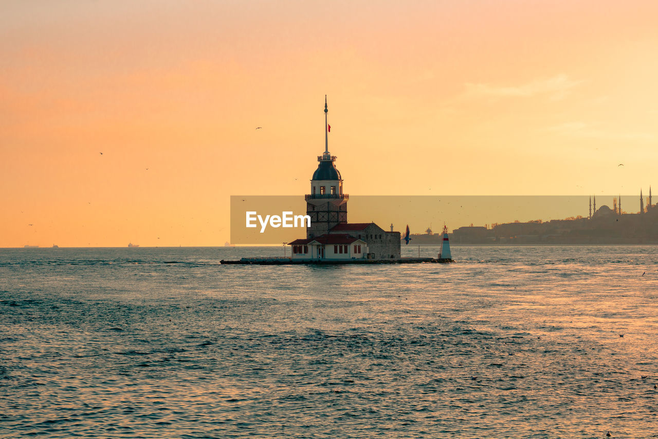 VIEW OF BUILDING BY SEA DURING SUNSET