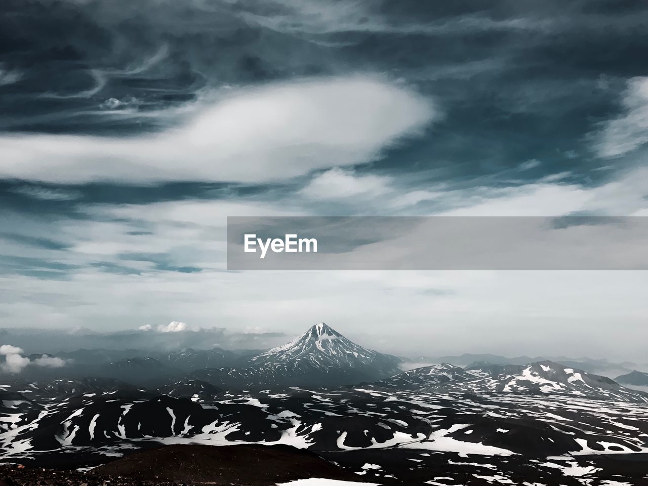 Aerial view of snowcapped mountain against cloudy sky