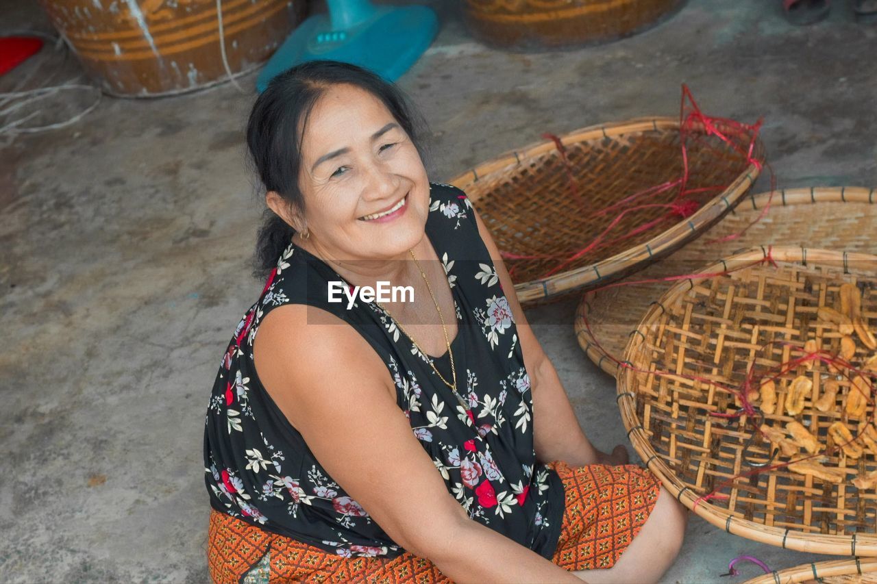 Portrait of smiling woman sitting by baskets at store