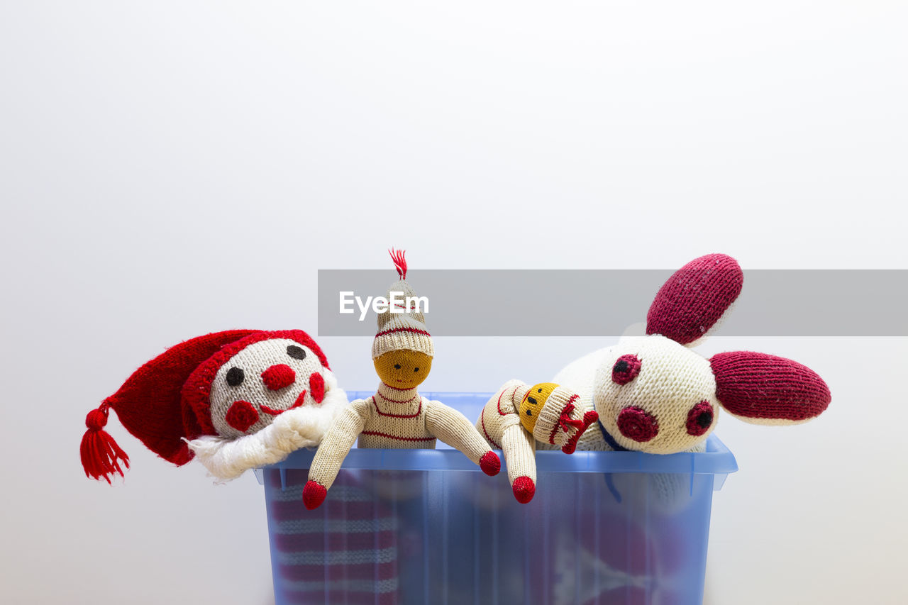 Close-up of knitted toys in container over gray background