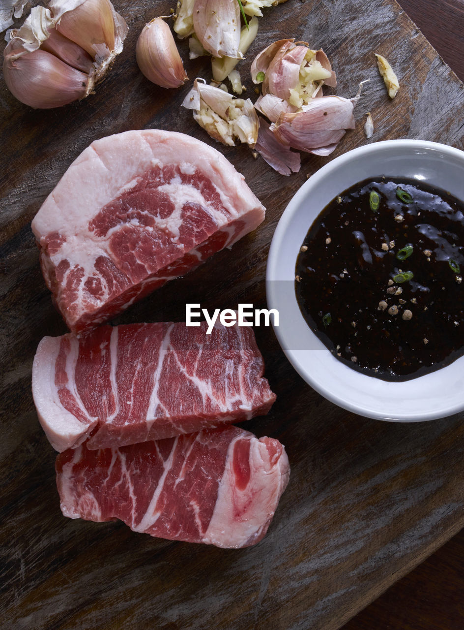 High angle view of raw beef with soy sauce in bowl on cutting board