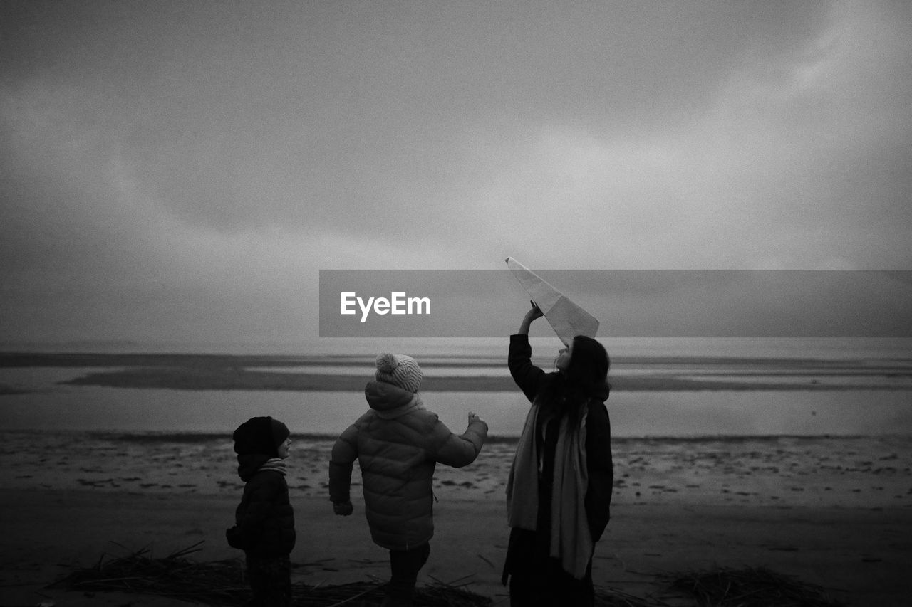 Rear view of children on beach against sky