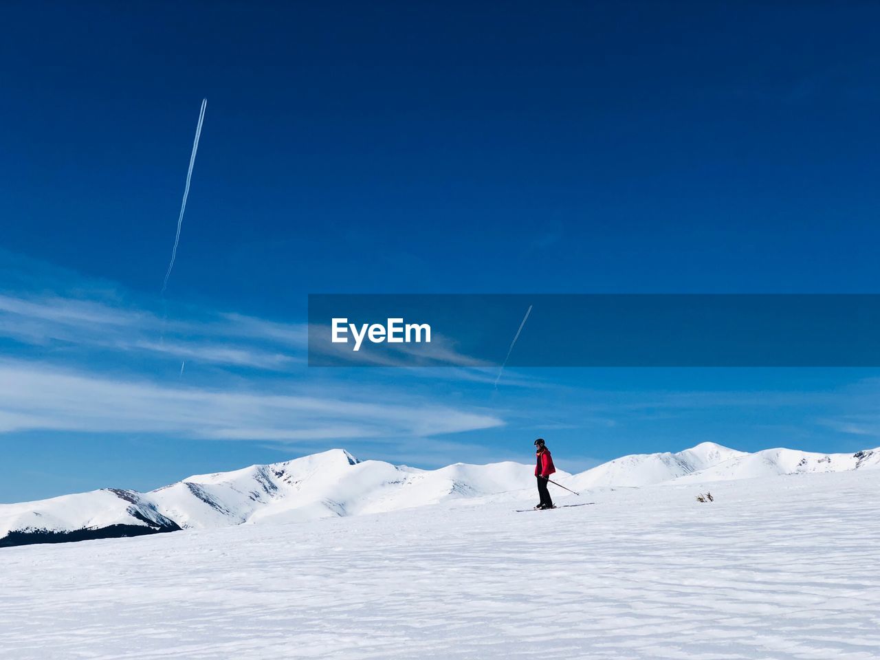 Woman skiing on snow covered land against sky