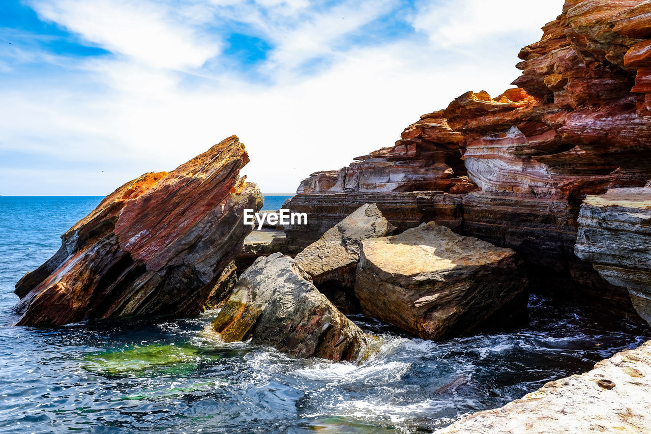 Rock formations by sea against sky