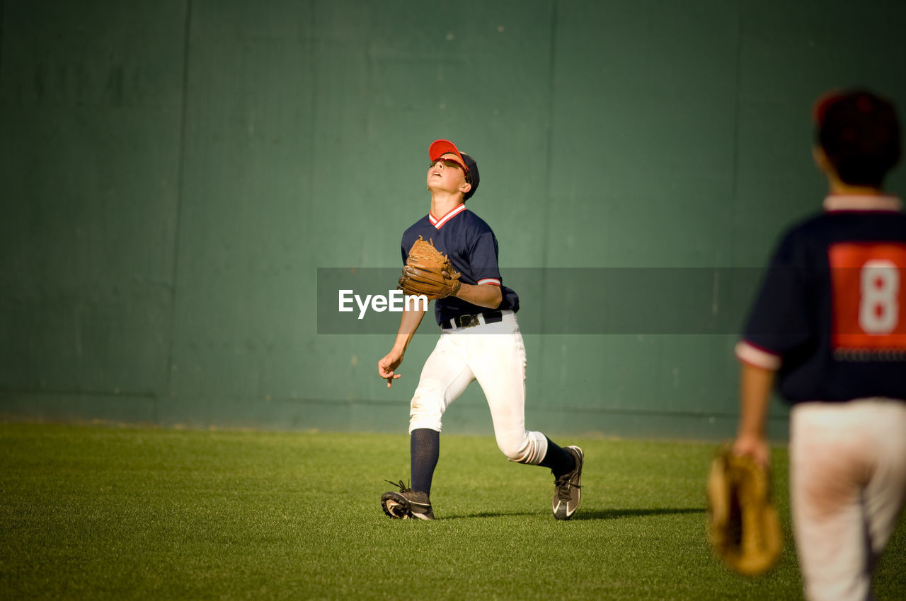 Young baseball player in sunglasses looking up at a fly ball