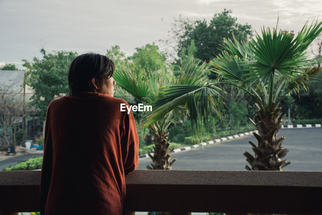 Rear view of man standing against palm trees