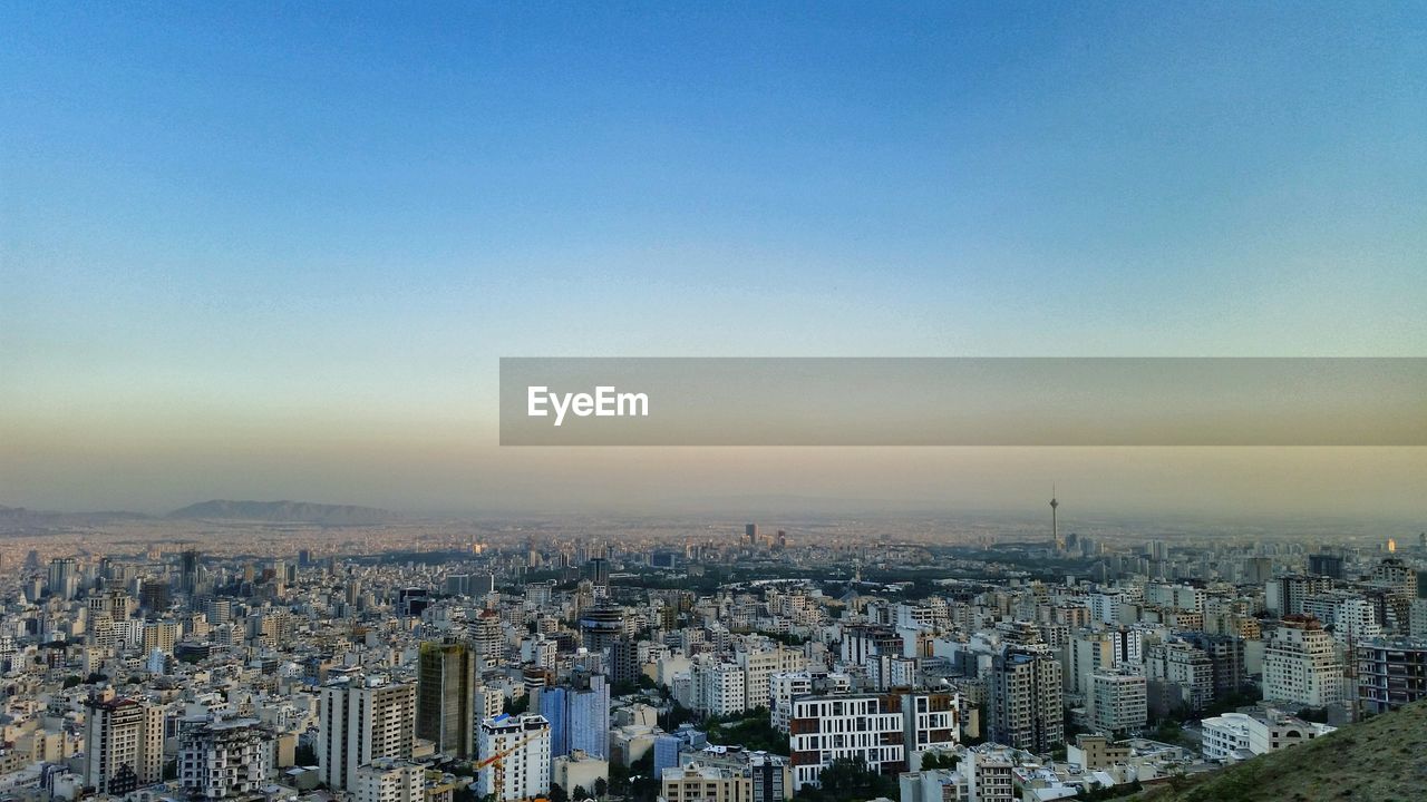 HIGH ANGLE VIEW OF CITY BUILDINGS AGAINST SKY DURING SUNSET