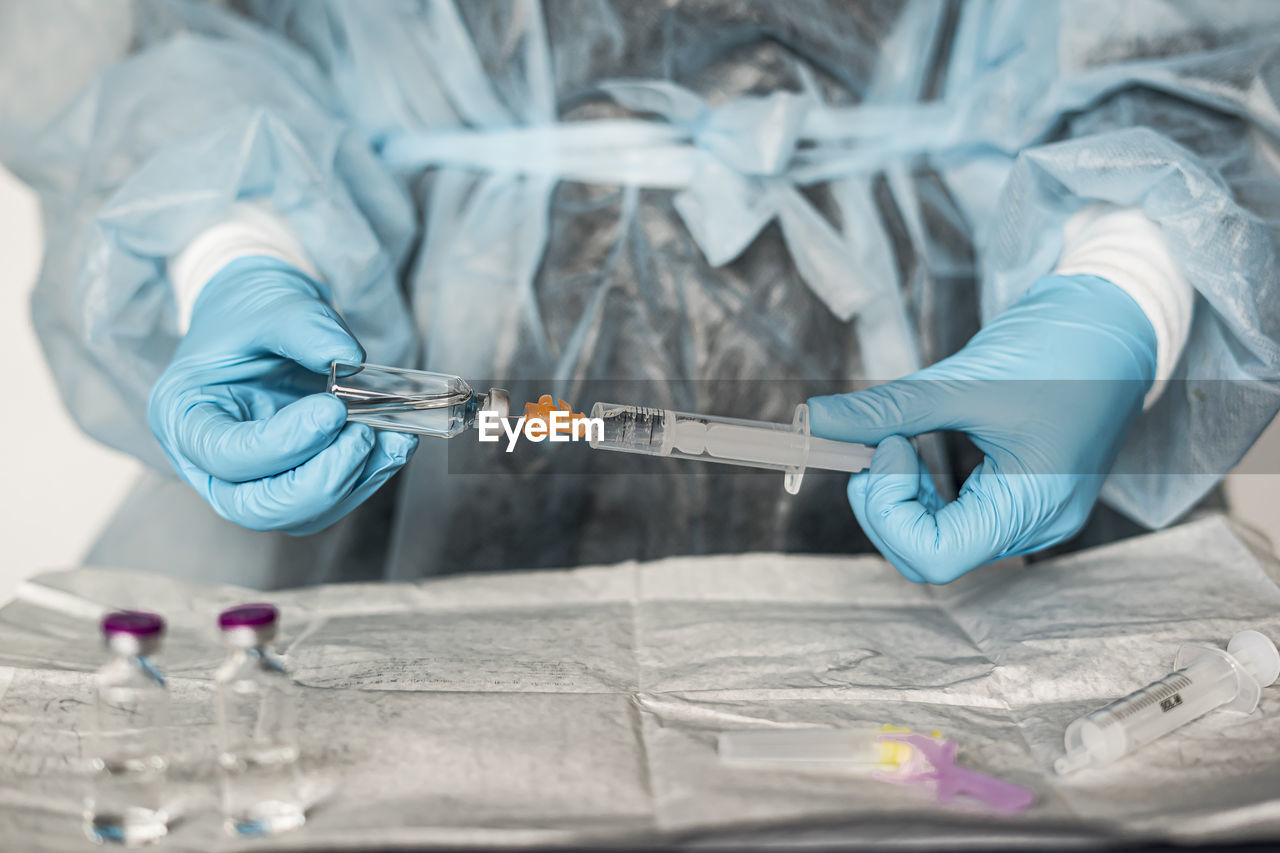 Midsection of scientist holding syringe at laboratory