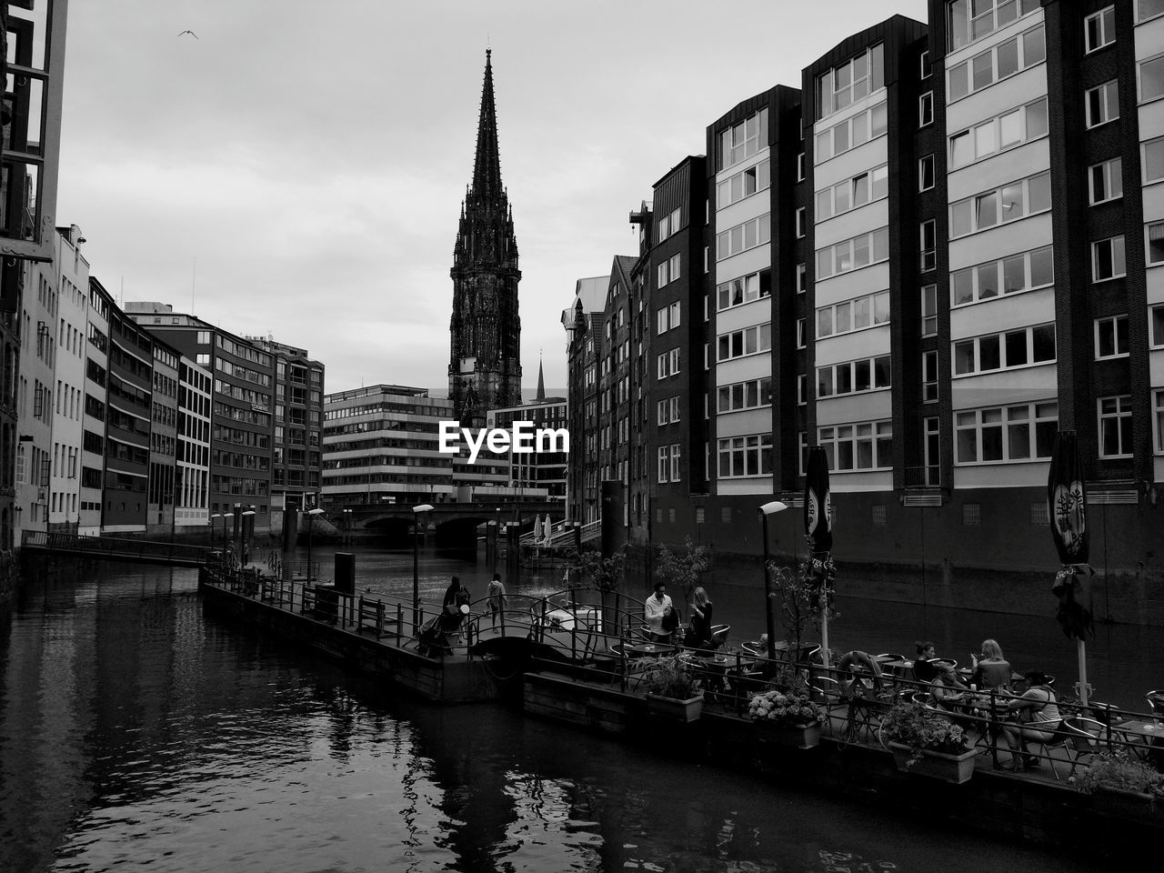 BRIDGE OVER RIVER AMIDST BUILDINGS IN CITY