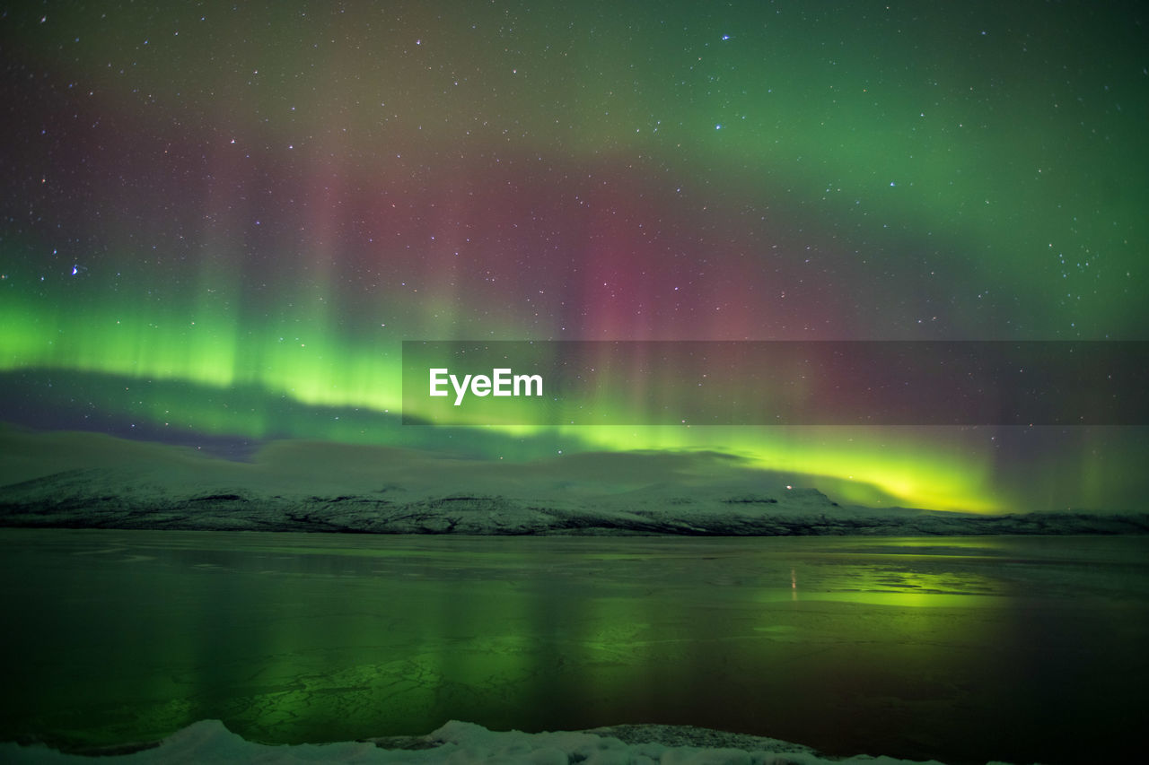 Scenic view of sea and aurora against sky at night