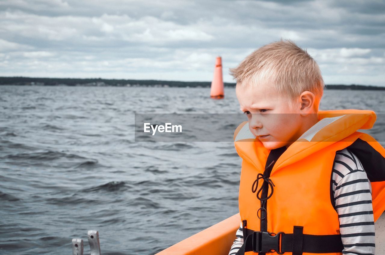 Boy looking at sea against sky