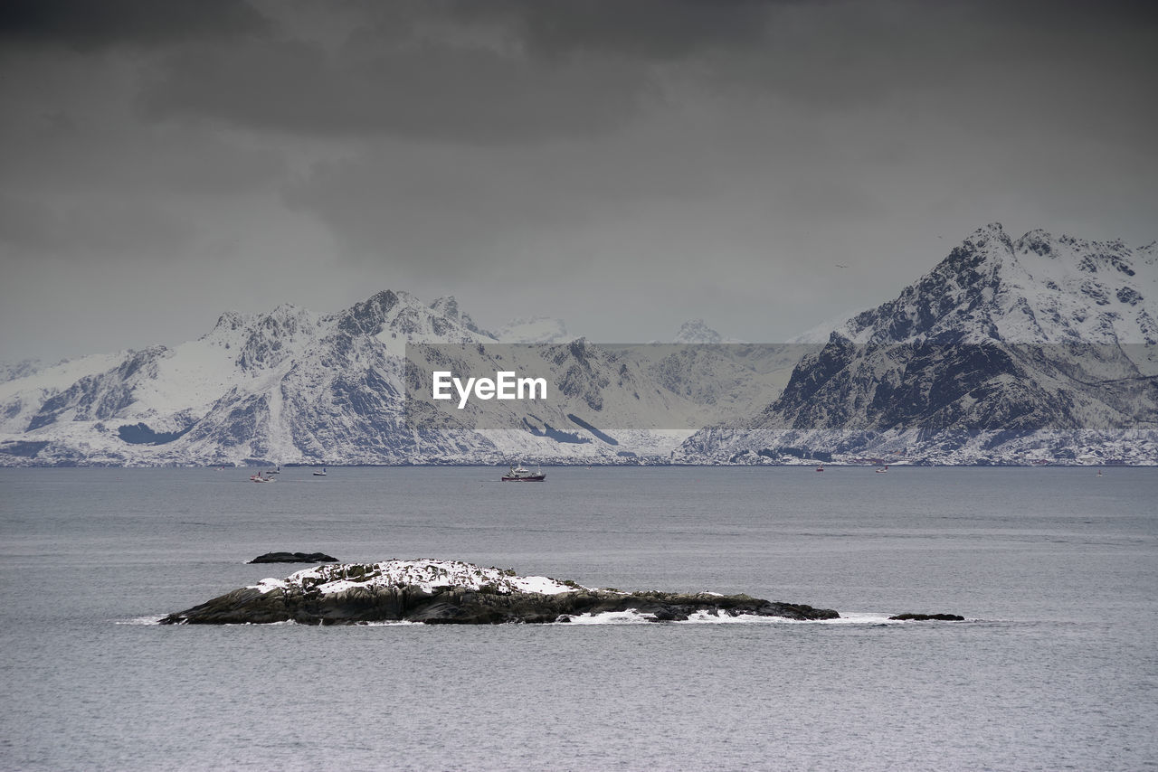SCENIC VIEW OF SEA AGAINST SNOWCAPPED MOUNTAINS DURING WINTER