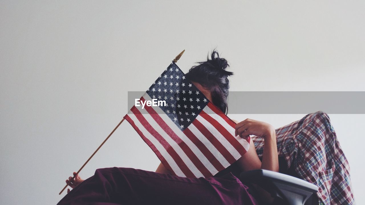 Woman hiding face with american flag over white background