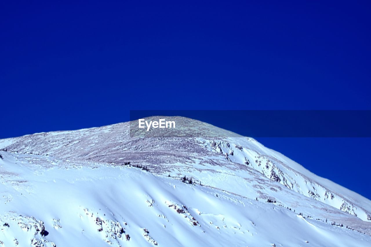 LOW ANGLE VIEW OF SNOWCAPPED MOUNTAIN AGAINST CLEAR SKY
