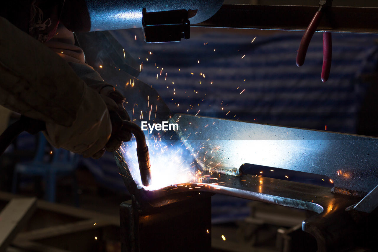 Cropped hands of man working on metal in factory