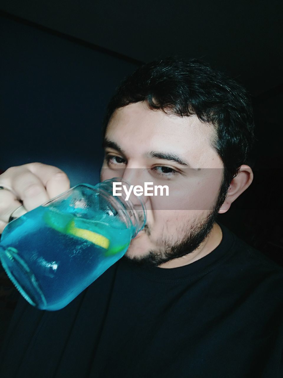 Portrait of man drinking juice in darkroom
