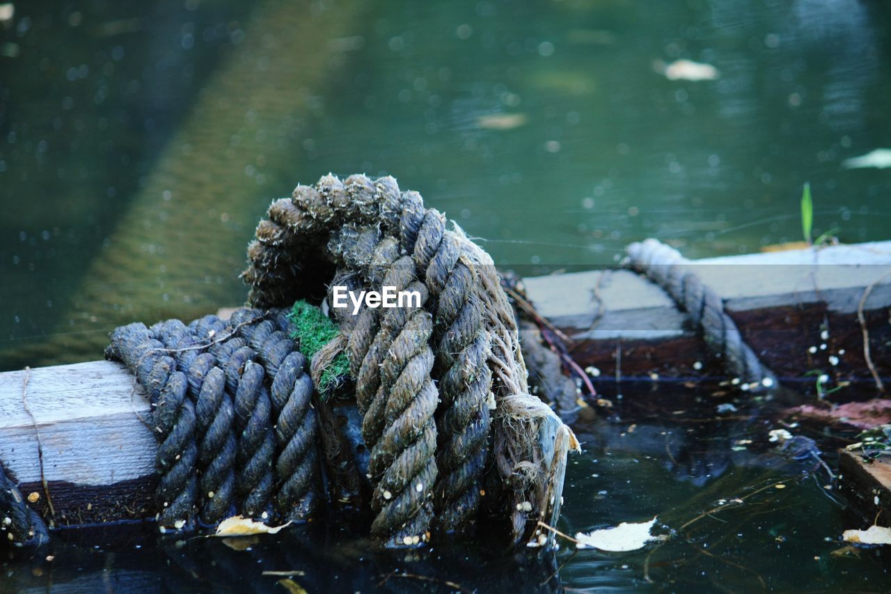 CLOSE-UP OF ROPE TIED UP ON RIVERBANK