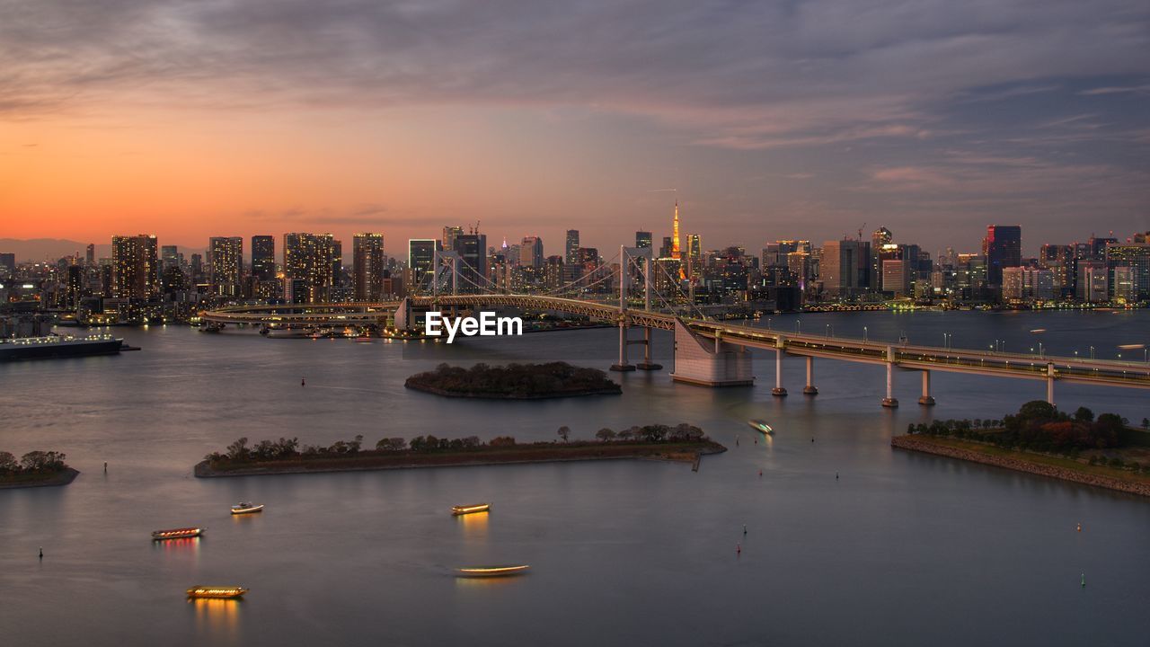 Scenic view of river and buildings against sky during sunset