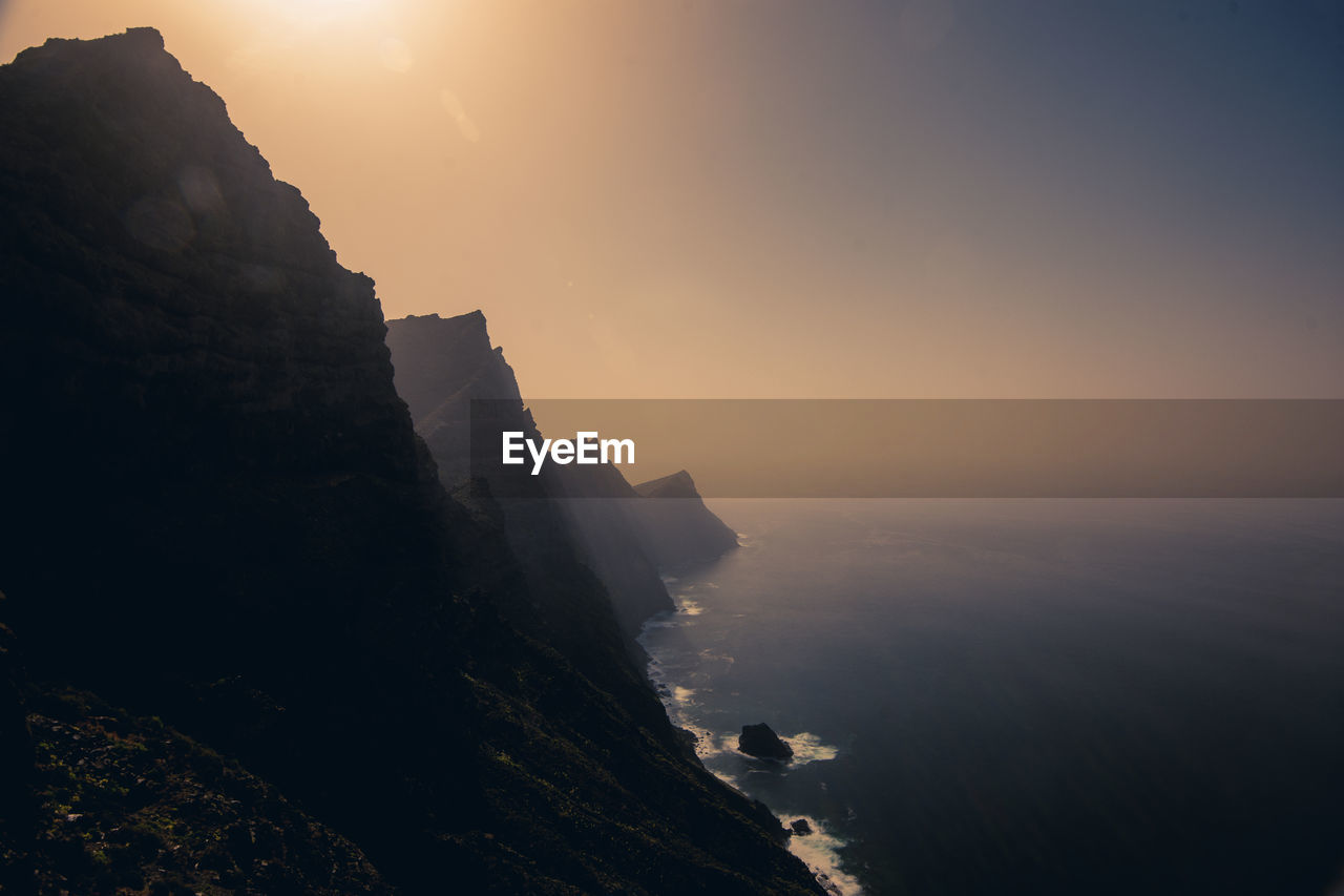 Scenic view of cliff against sky during sunset