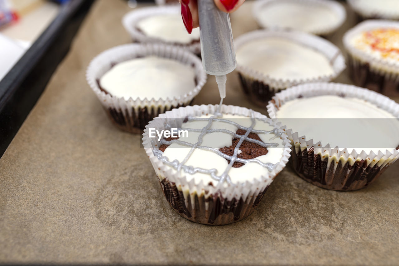 Chocolate-brown cupcakes wrapped in white paper and covered with white frosting.