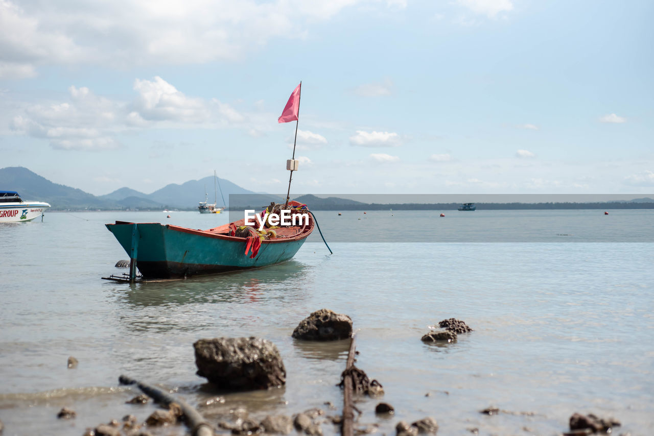 BOAT MOORED ON SHORE AGAINST SKY