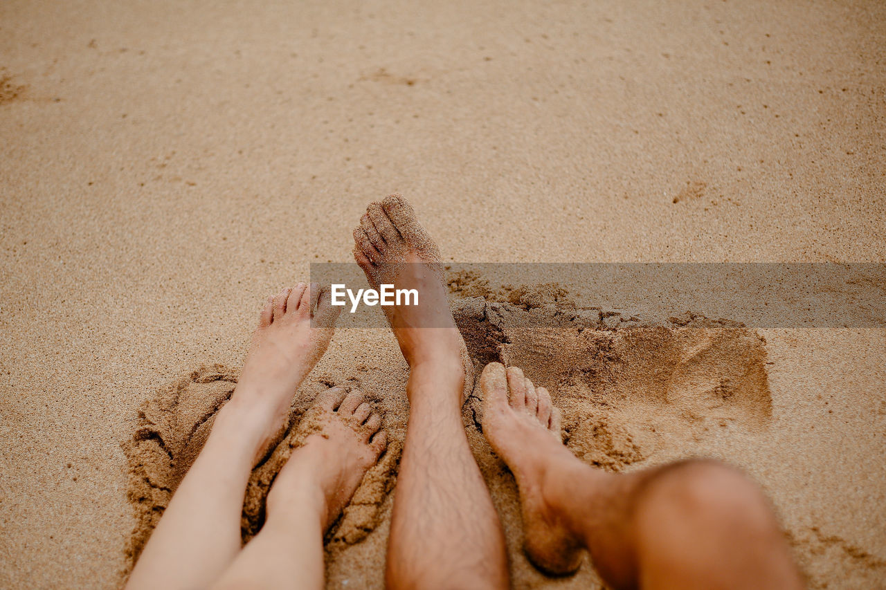 Low section of woman relaxing on sand at beach