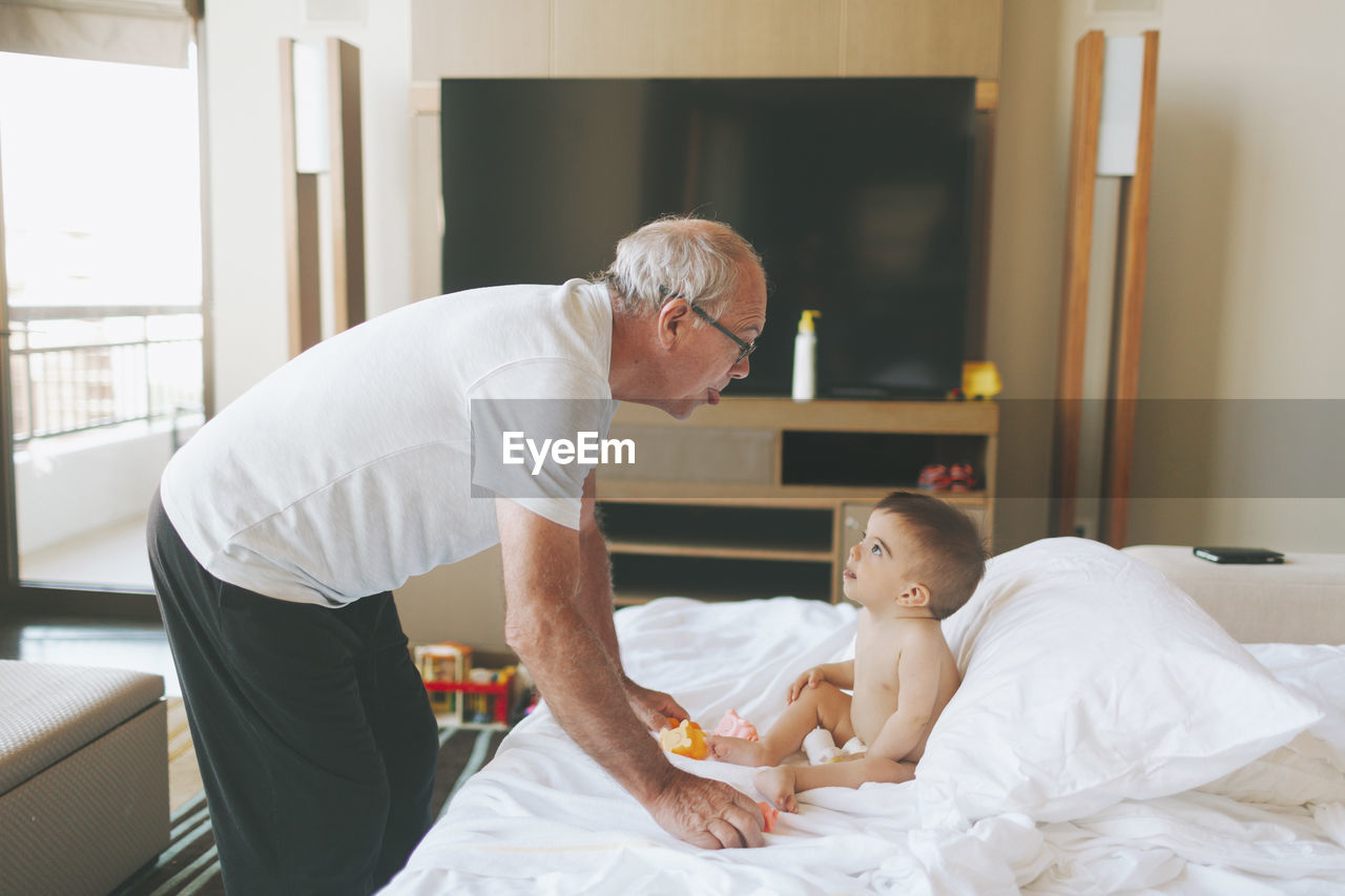 Grandfather playing with a baby at home sticking out tongue