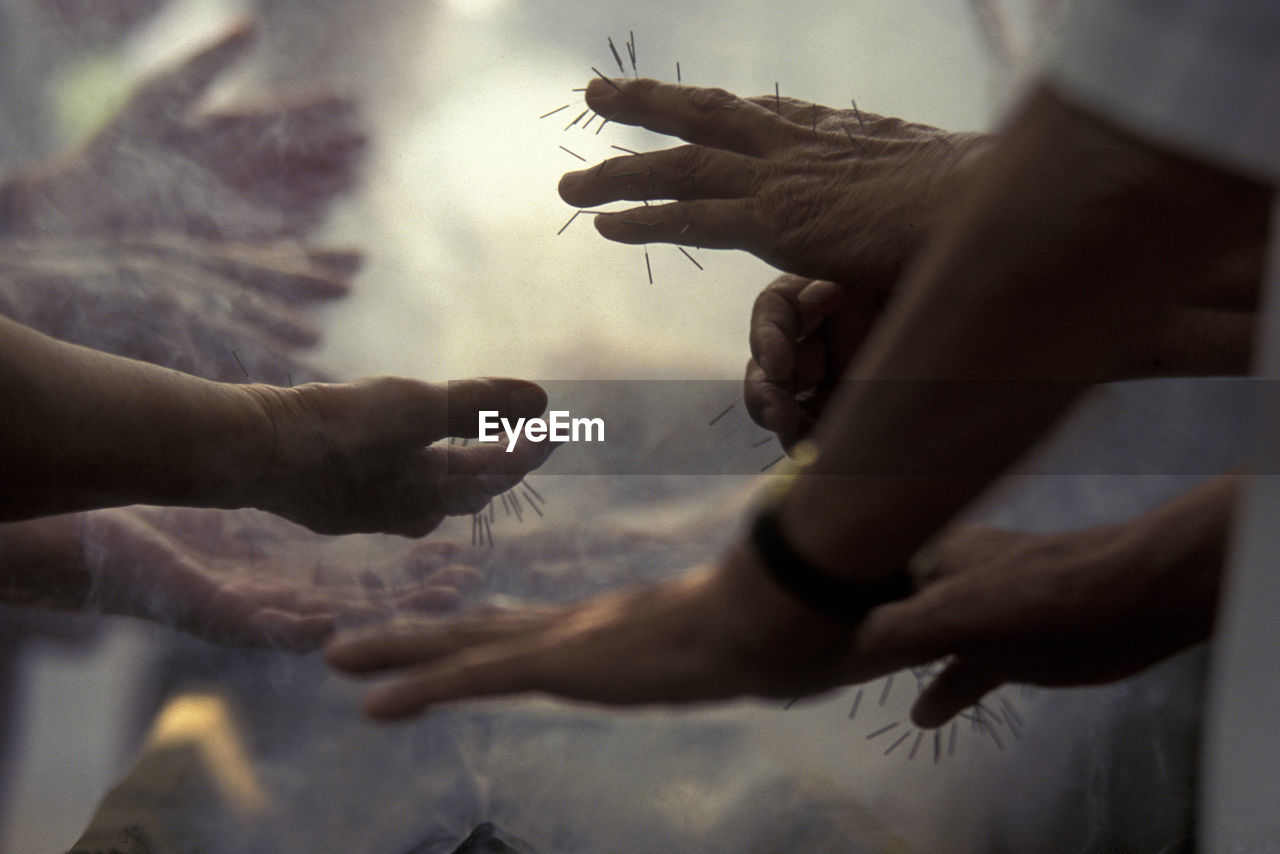 Cropped hands of people with nail piercing in smoke