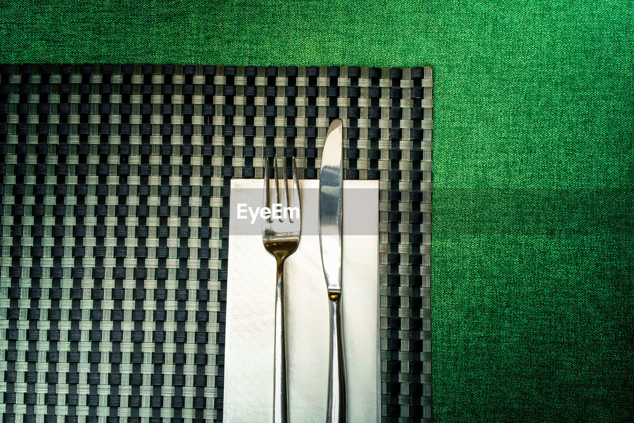 Close-up of fork with knife on place mat