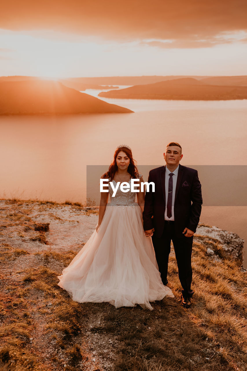 rear view of bride and groom standing on field