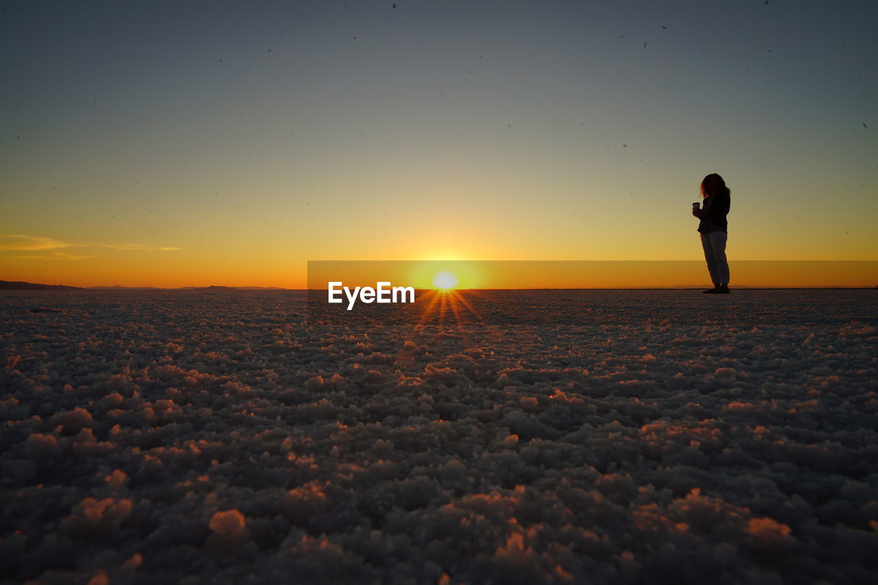 Person standing at bonneville salt flats during sunset