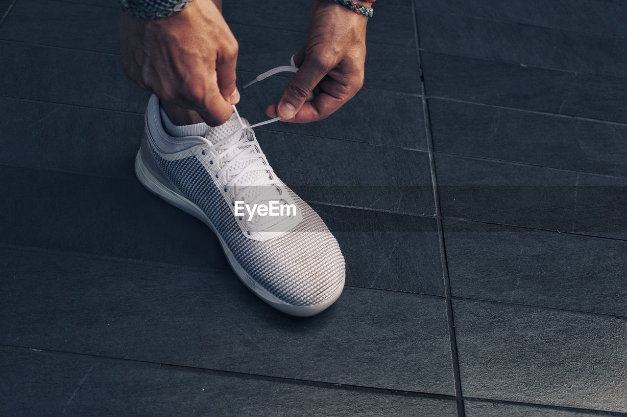 Low section of man tying shoe on footpath 