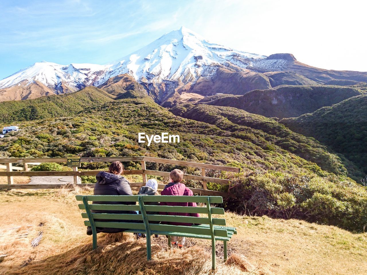 Rear view of family sitting on bench against mountains