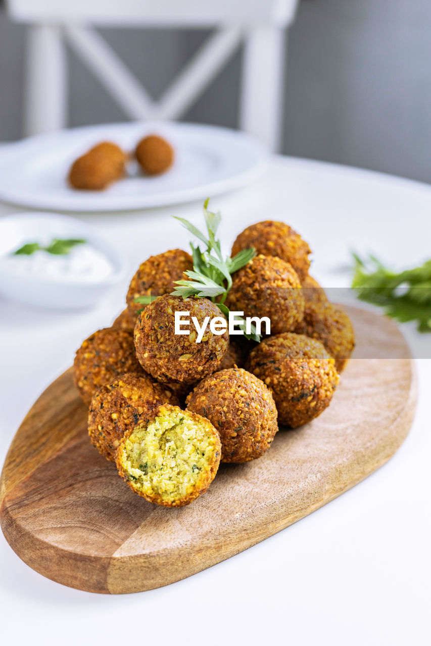 A traditional israeli dish fresh falafel on a wooden board, garnished with a sprig of parsley.