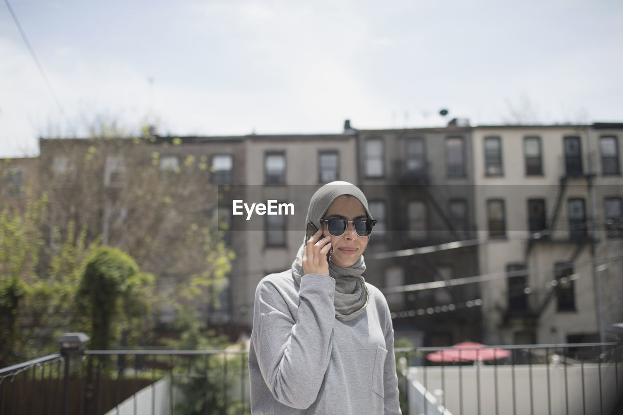 Muslim woman wearing a hijab and sunglasses taking a phone call