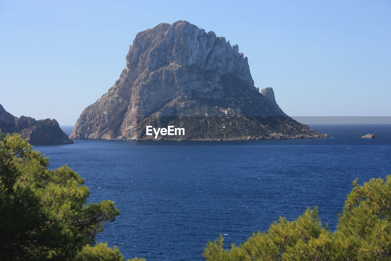 SCENIC VIEW OF SEA AND ROCKS AGAINST CLEAR BLUE SKY