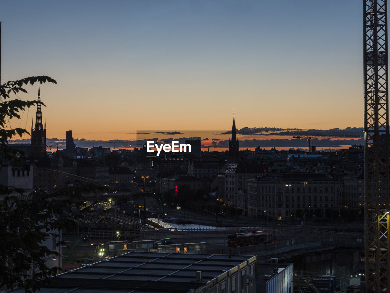 HIGH ANGLE VIEW OF ILLUMINATED BUILDINGS IN CITY AGAINST SKY DURING SUNSET