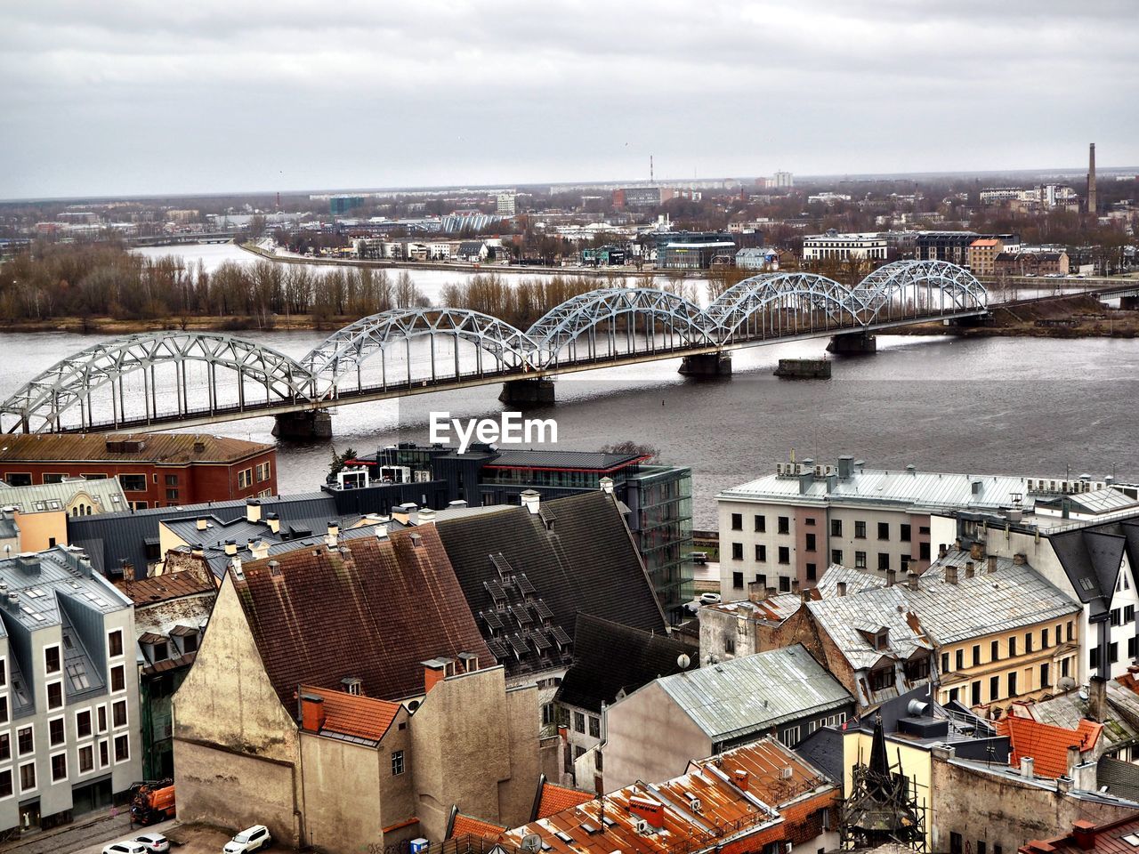 High angle view of bridge over river by buildings in city against sky