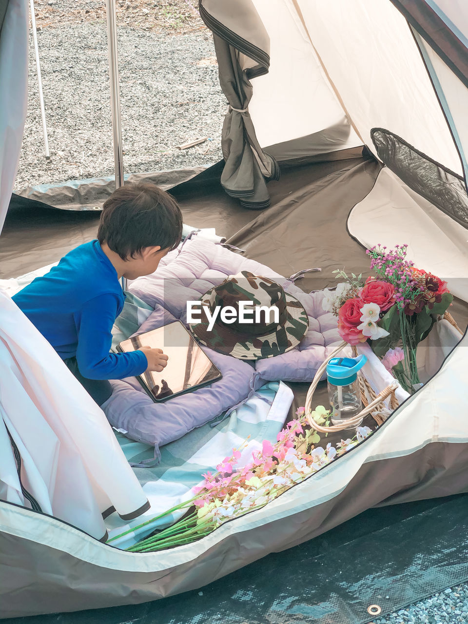 High angle view of boy sitting in tent by potted plants