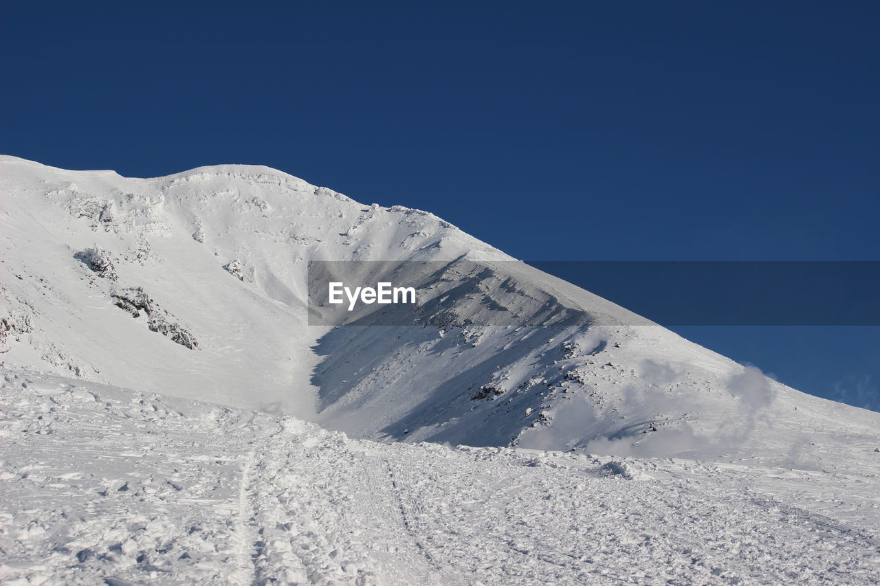 Scenic view of snowcapped mountains against clear blue sky