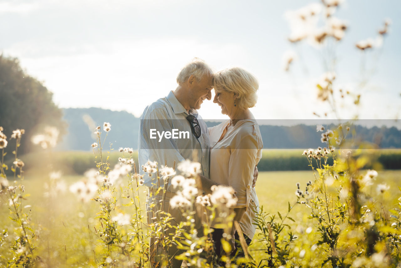 Side view of happy senior couple romancing in park during sunny day