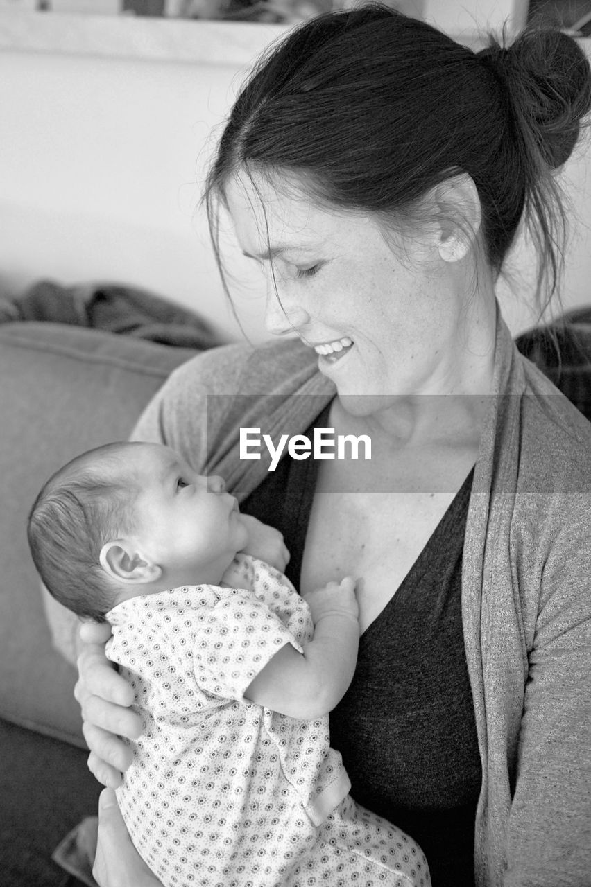 Smiling mother carrying toddler at home