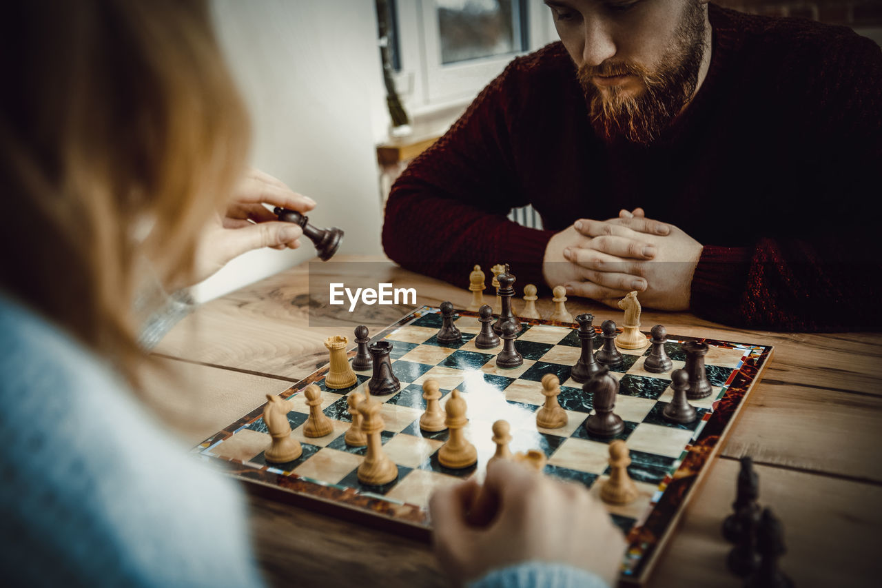 Couple playing chess on table at home