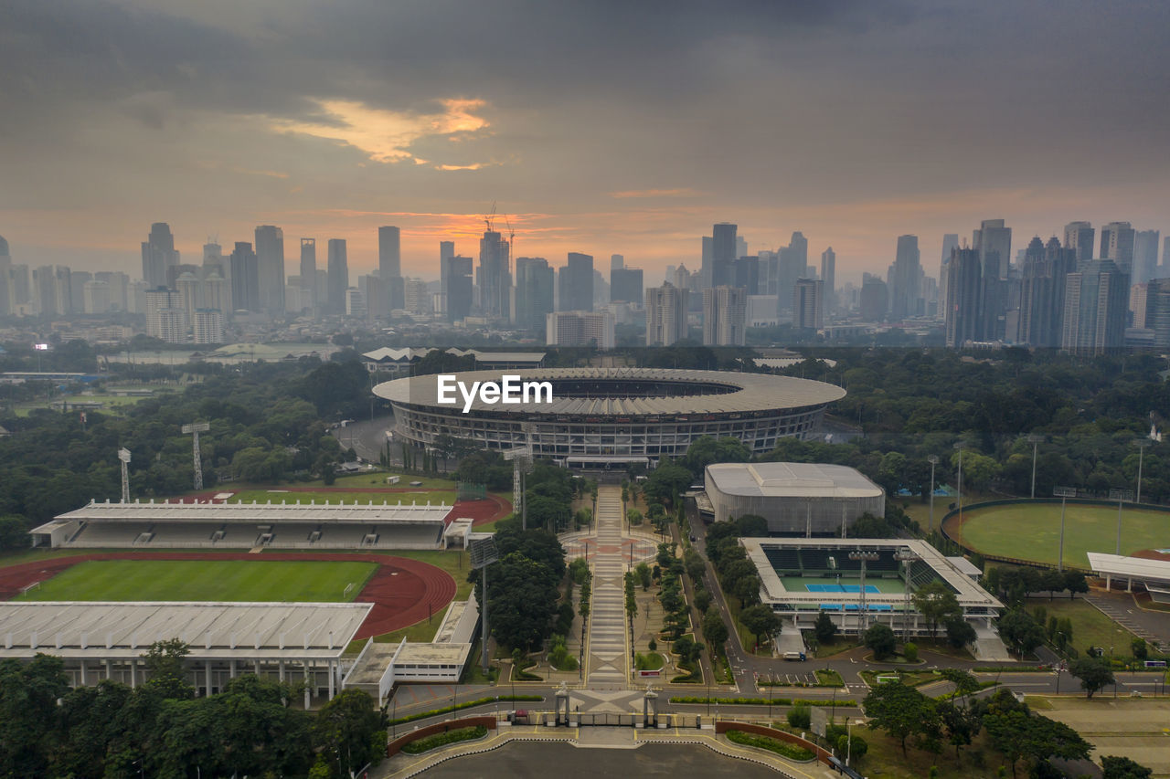 HIGH ANGLE VIEW OF BUILDINGS IN CITY AGAINST SKY DURING SUNSET