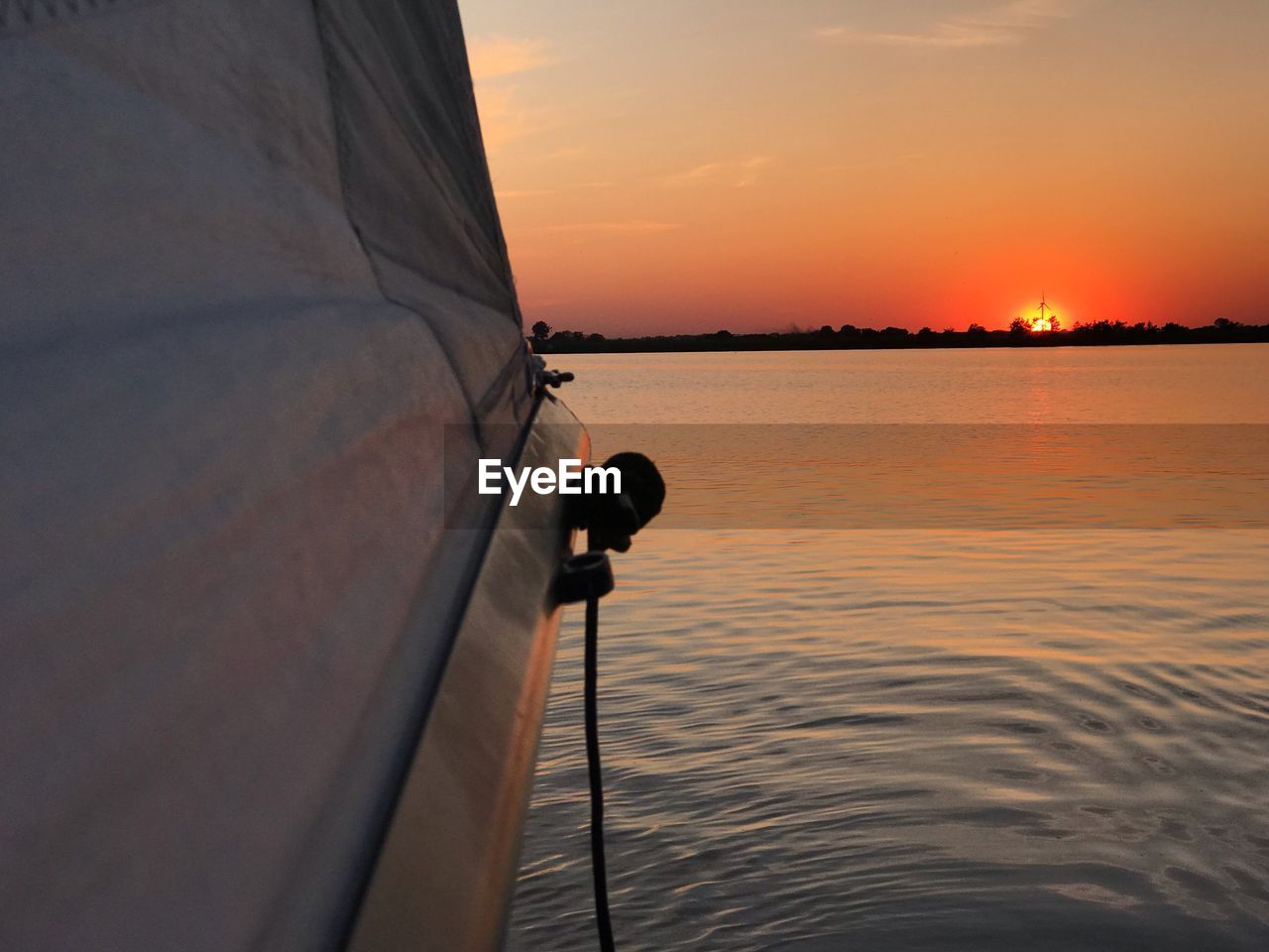 MAN SAILING ON SEA AGAINST SKY DURING SUNSET