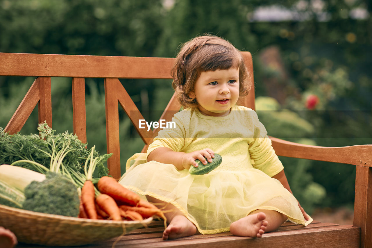 Happy girl sitting on bench against plants