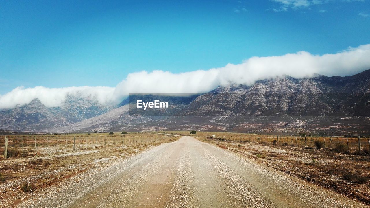 Road leading towards mountains against sky