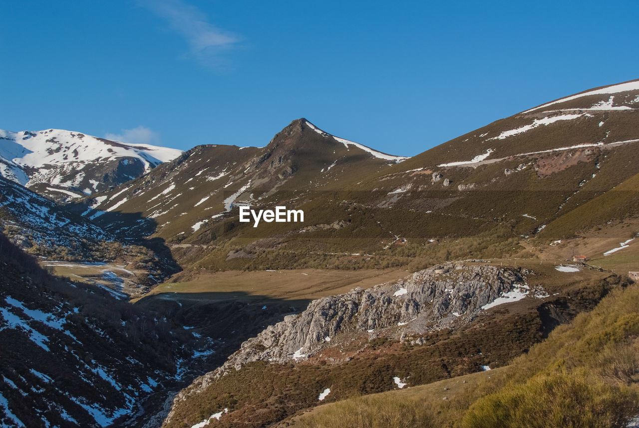 Scenic view of mountains against blue sky